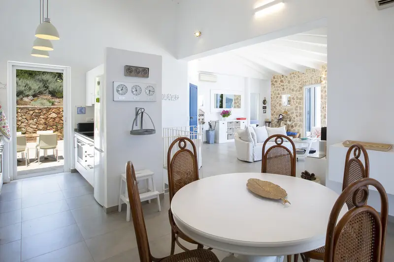 Kitchen table beneath a white beamed ceiling with garden doors behind